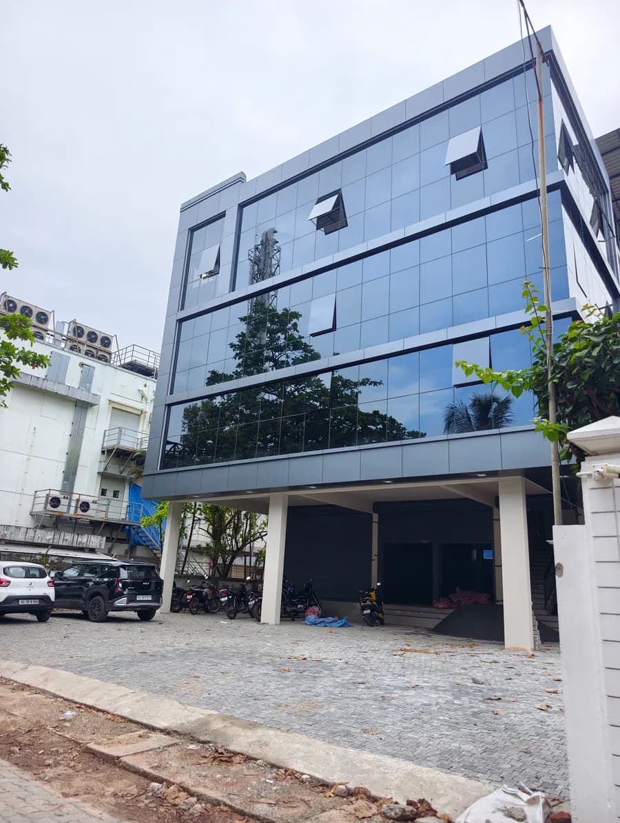 Three-storey building with a blue glass facade on a gravel forecourt
